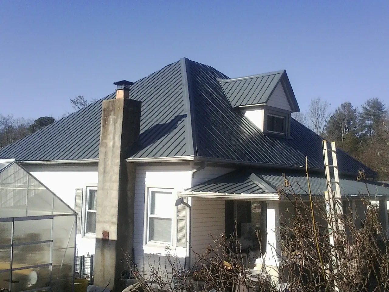 Dark blue standing seam metal roof on a white farmhouse with dormer — Slate & Tile Roof Repair by Roofing Brothers in Pine Grove
