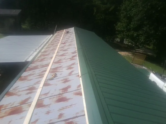 Old rusted panels beside newly installed green metal roofing — Wind Damage Roof Repair by Roofing Brothers in Pine Grove
