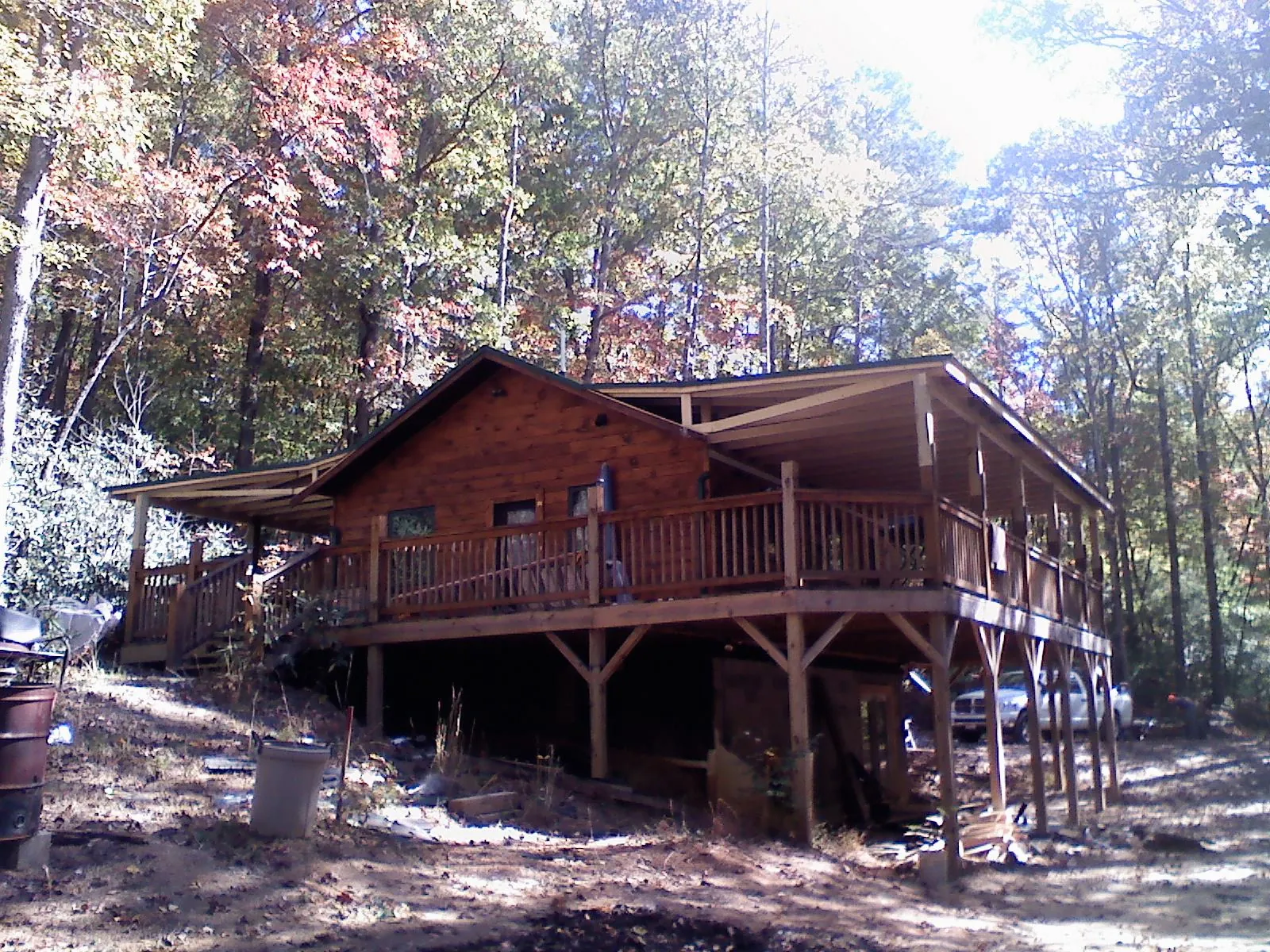 Log cabin with a wraparound porch and metal roof in the fall in Pine Grove