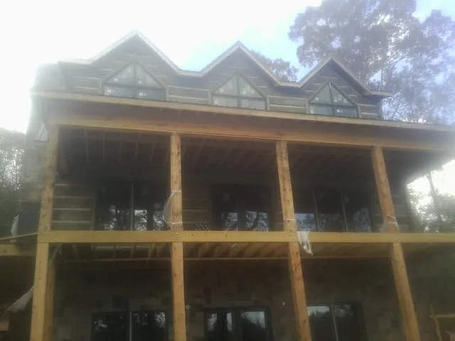Dormers and porch framing on a large log home under construction — Roof Coating work by our crew in Pine Grove