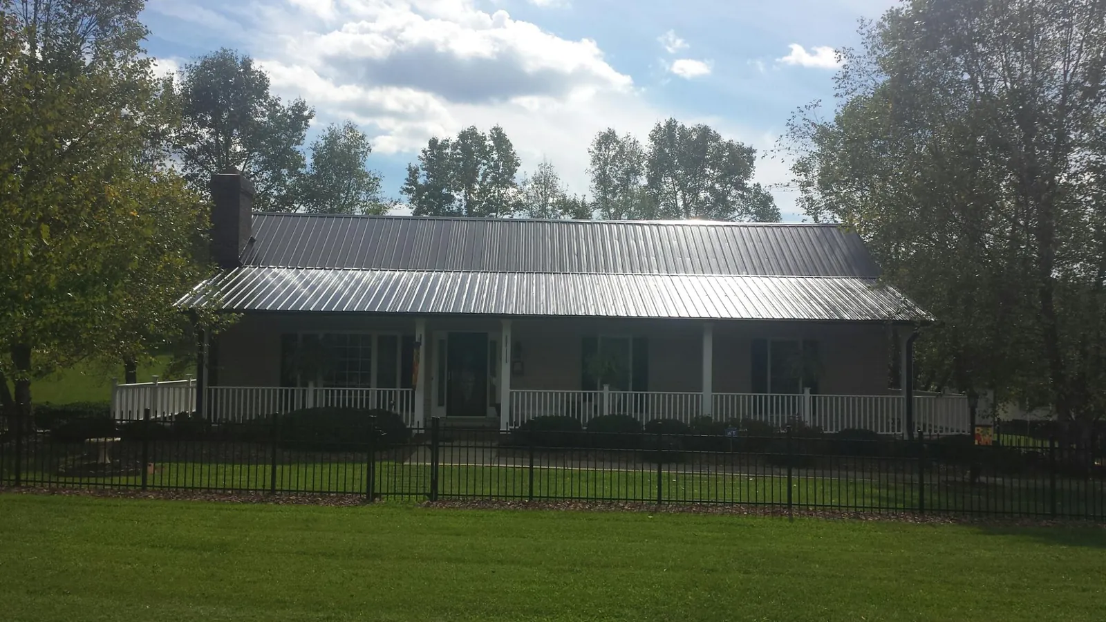 Gray metal roof on a brick ranch with a full width front porch — Gutter Guard Installation work by our crew in Pine Grove