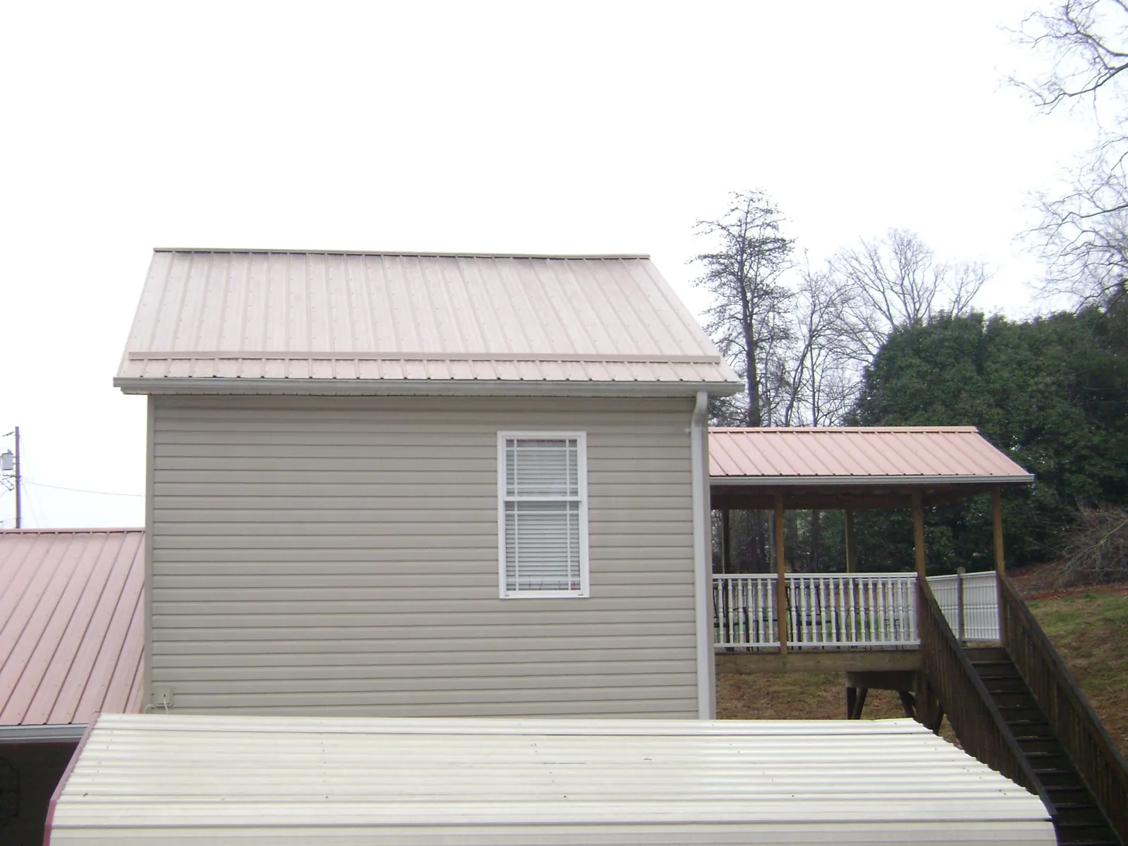 Tan metal roofs on a two story addition and attached porch, from a Roof Replacement job in Pine Grove