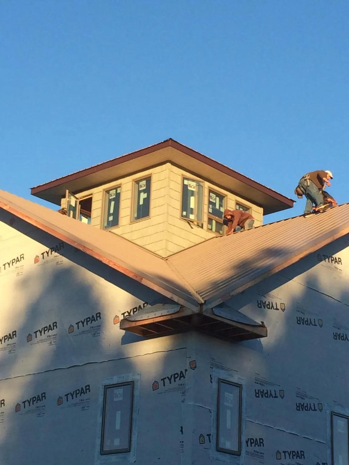 Roofers working around a rooftop cupola on a new metal roof at sunset — Roof Waterproofing in Pine Grove by Roofing Brothers